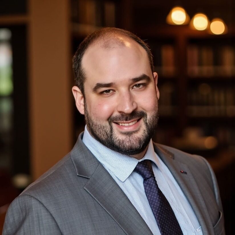 A man in suit and tie smiling for the camera.