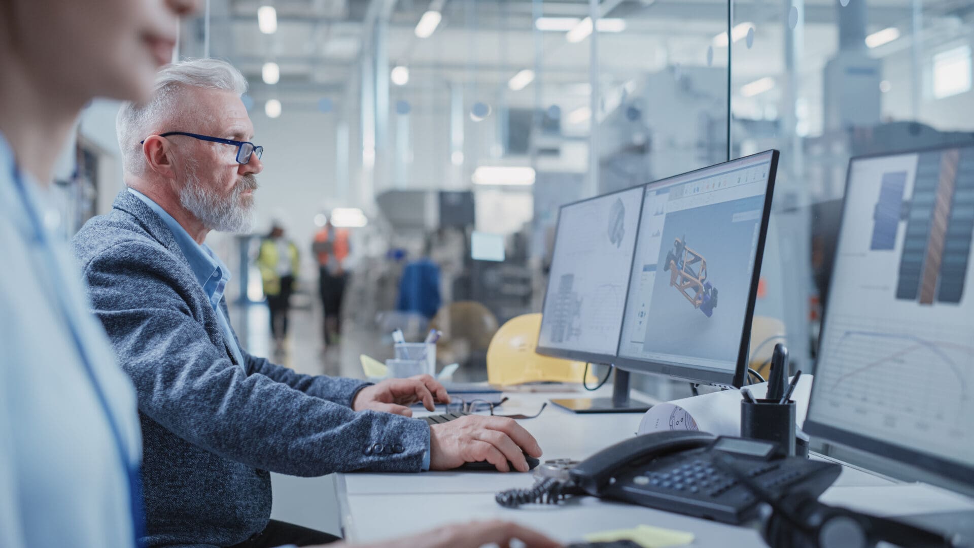 A man sitting at his computer desk in front of two monitors.